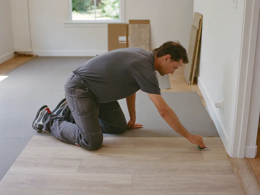 Twee vloerleggers leggen een klik-PVC vloer in een woonkamer